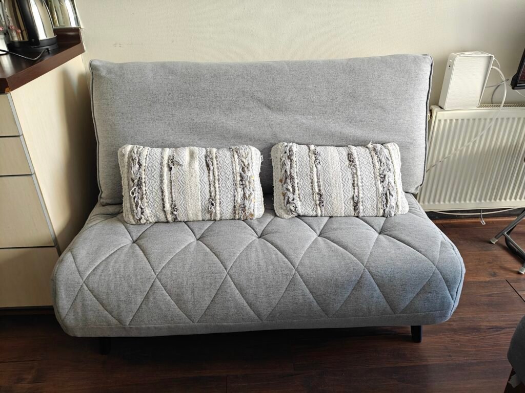 Sofá cama gris con cojines en el Estudio 210